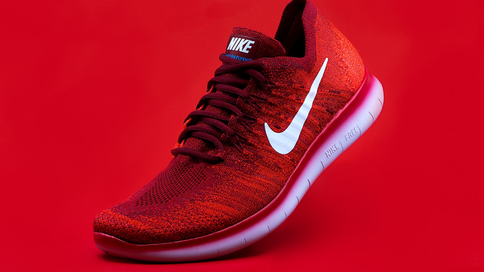 Chaussure de running posée sur fond rouge, illustration du choix de chaussures de course