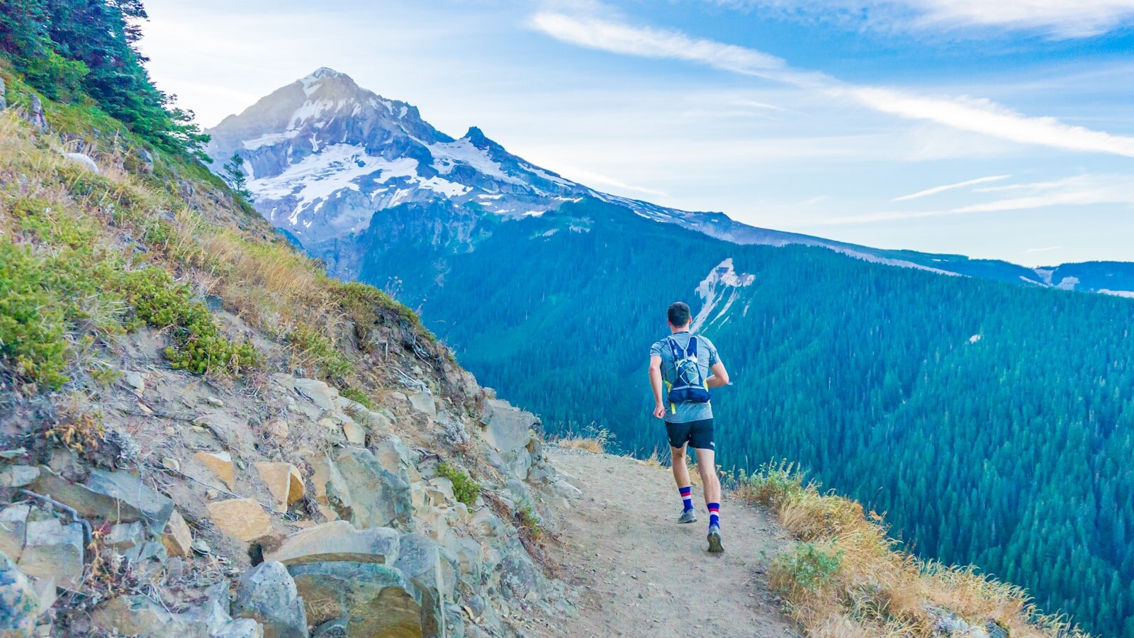 Coureur sur un sentier de crête avec vue panoramique sur les montagnes
