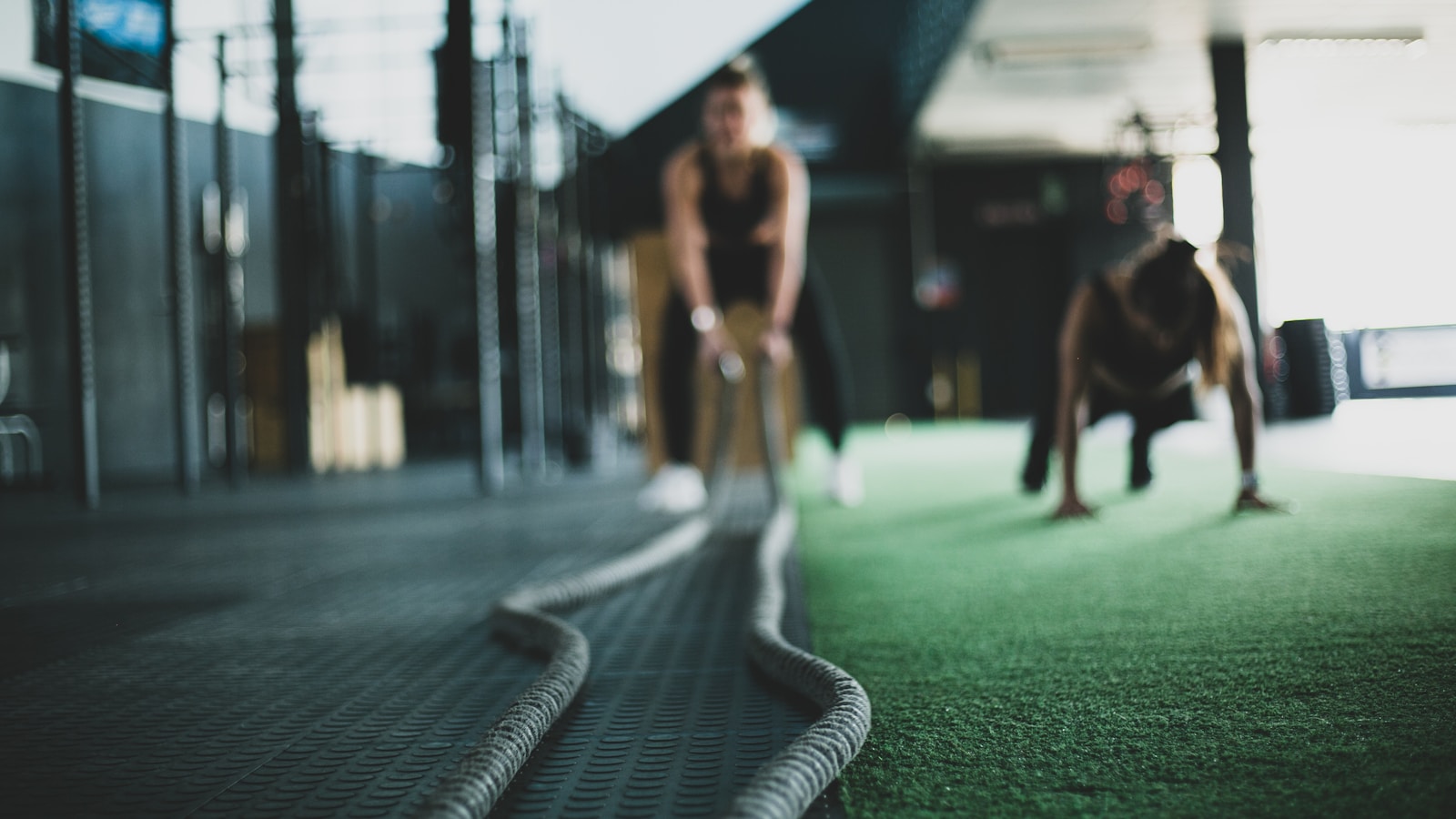 Athlètes à l'entraînement fonctionnel en salle (battle ropes et burpees), illustration d'une préparation HYROX