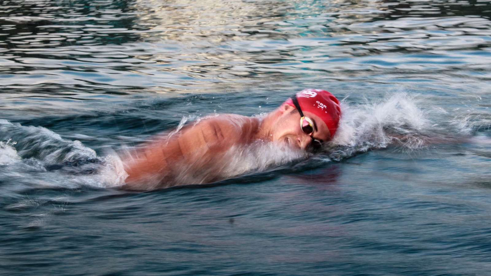 Nageurs en eau libre lors du départ d'un triathlon, bouchons colorés et combinaisons néoprène